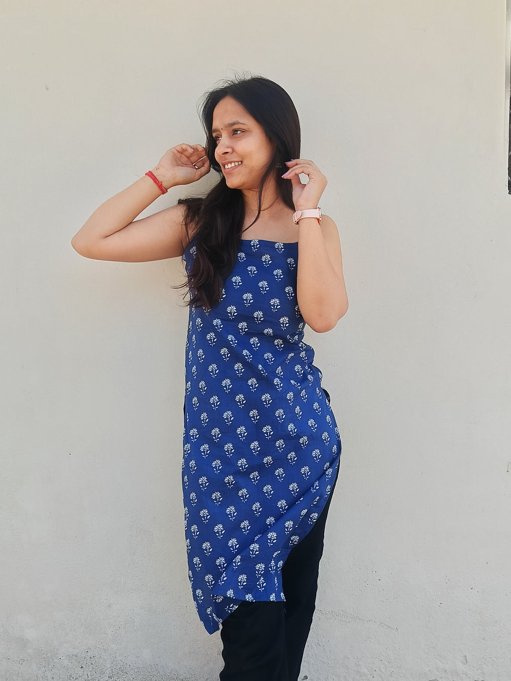 Woman wearing a blue kurti with white patterns against a plain background
