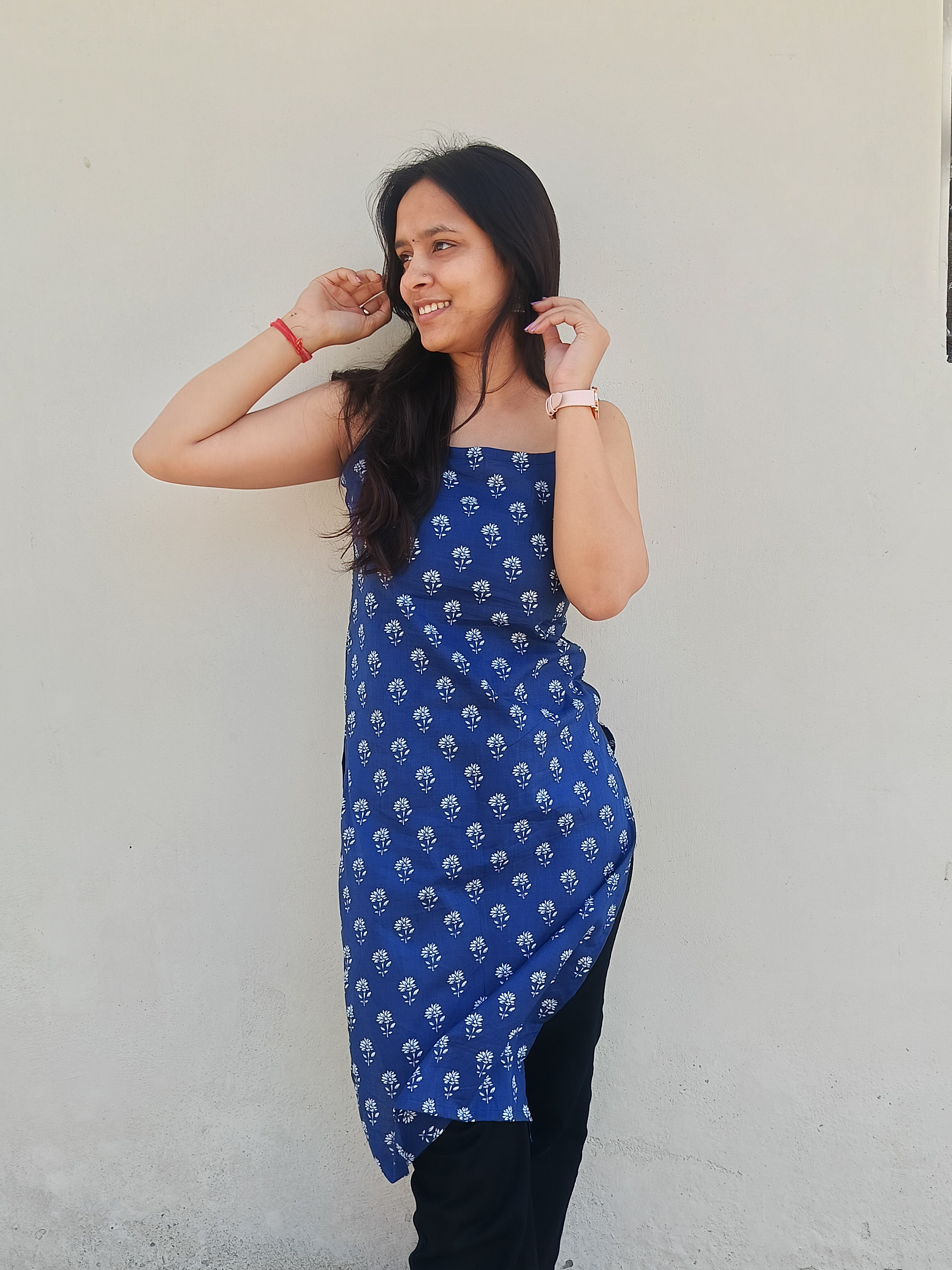 Woman wearing a blue kurti with white patterns against a plain background