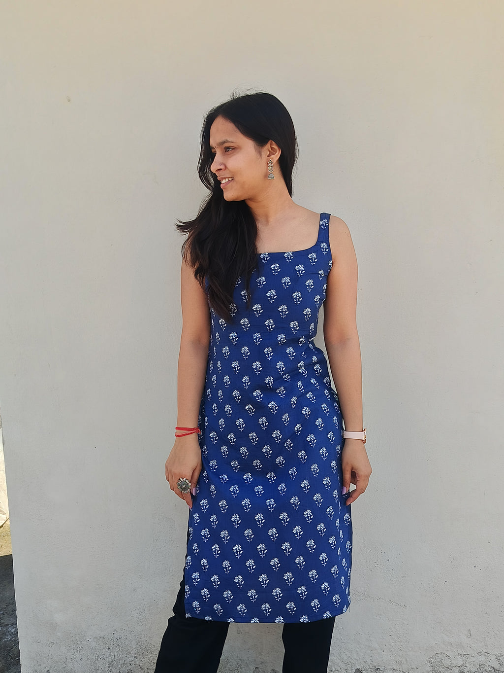 Woman wearing a blue dress with white patterns against a plain background