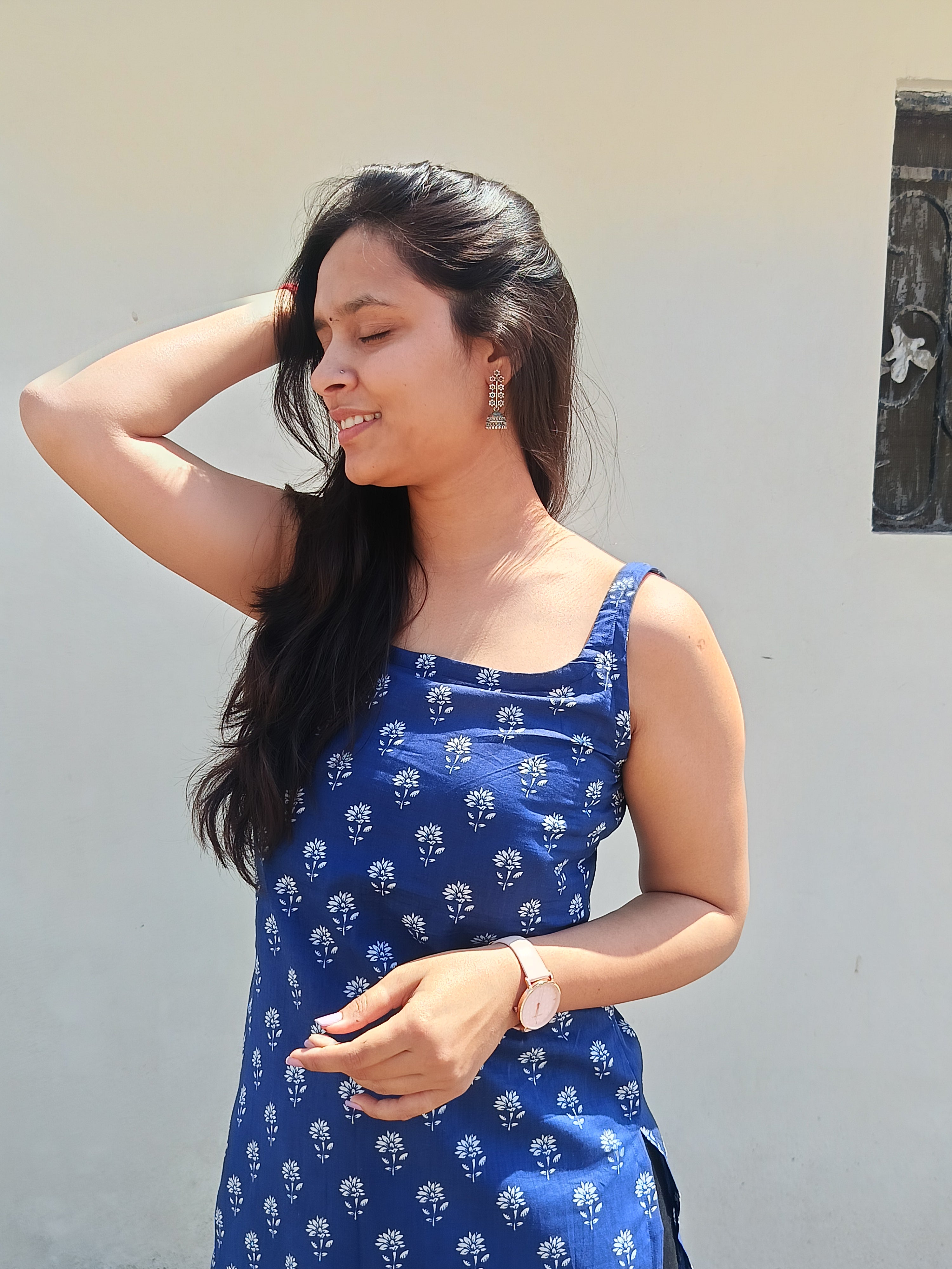 Woman wearing a blue dress with white patterns against a plain background