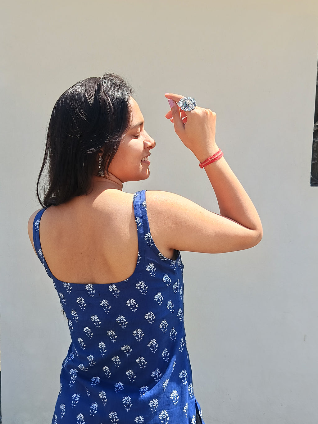 Woman in a blue dress with white patterns against a plain background