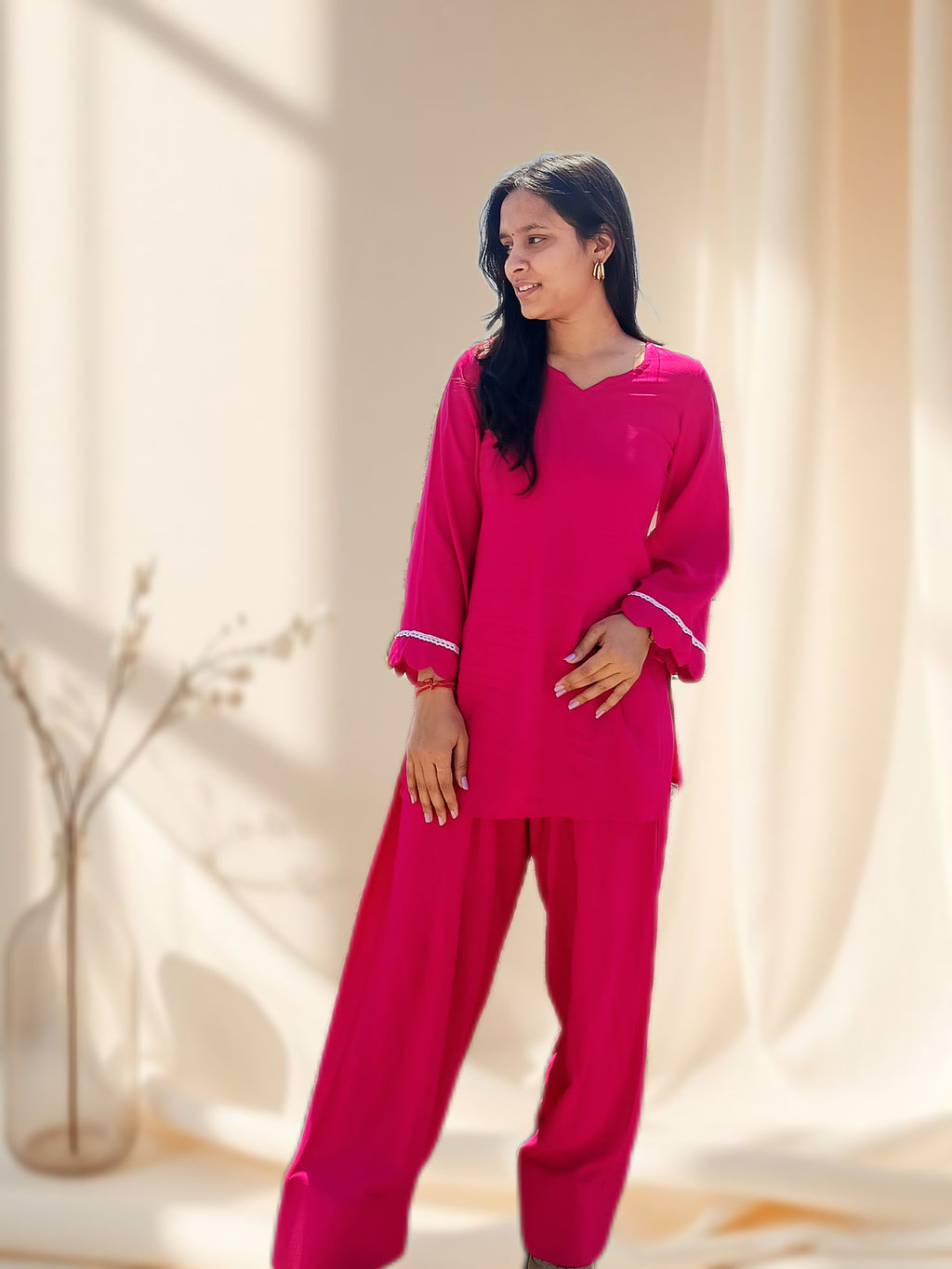 Woman wearing a pink salwar set in a softly lit room.