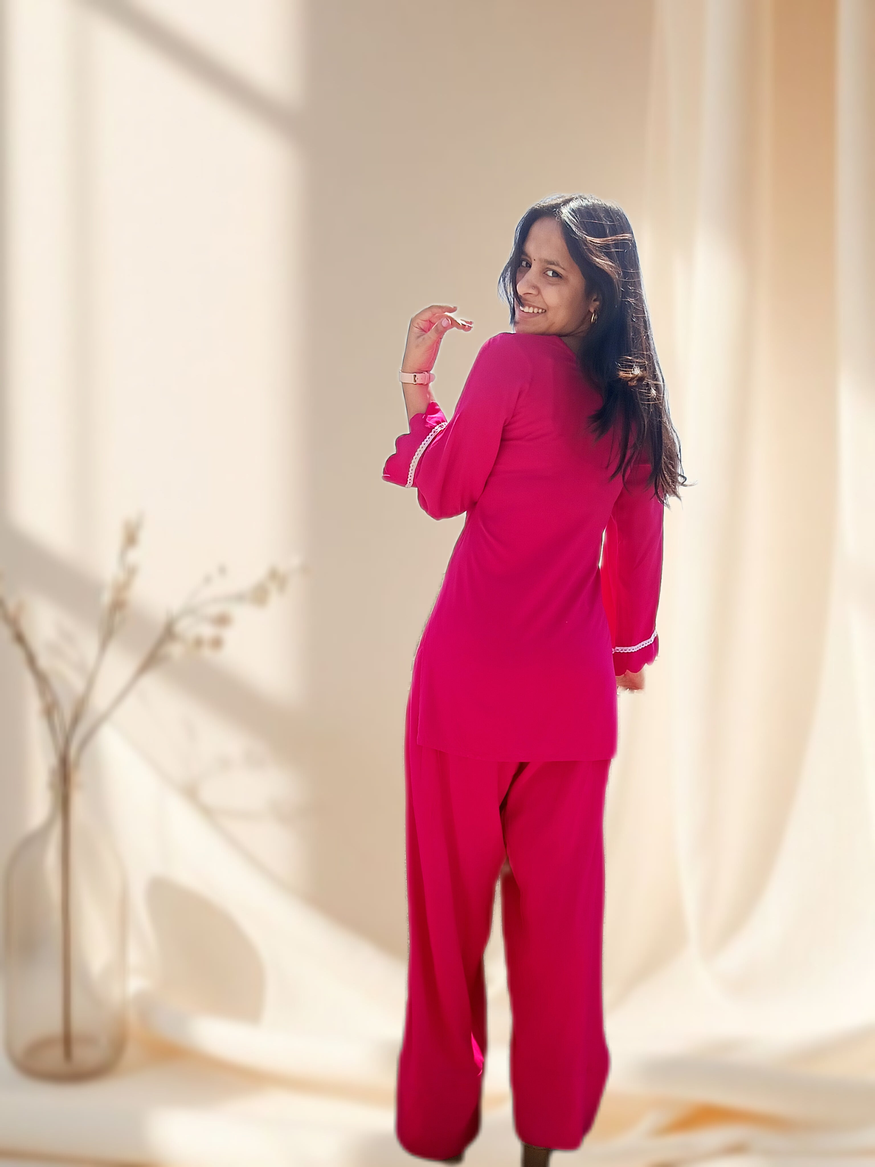 Woman in a bright pink outfit standing against a neutral background