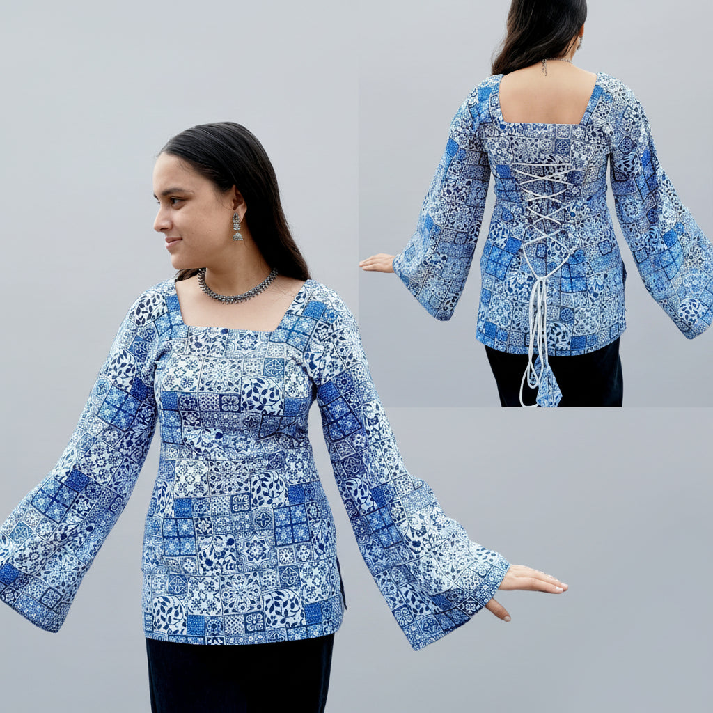 Woman wearing a blue patterned short kurti with a decorative back design, standing in front of a blue mosaic wall.