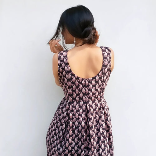 Woman wearing a sleeveless dress with a floral pattern on a plain background