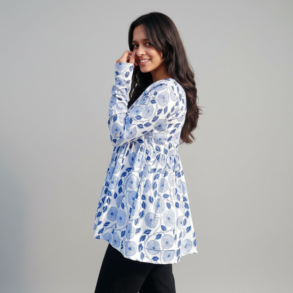 Woman wearing a blue floral patterned top against a textured wall.