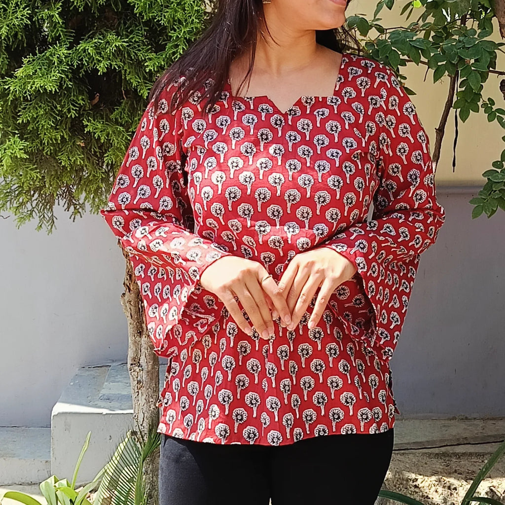 Person wearing a red patterned kurti  with greenery in the background