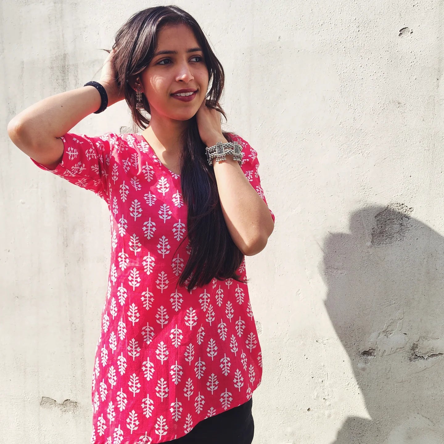 Woman wearing a butti print kurti against a light gray wall
