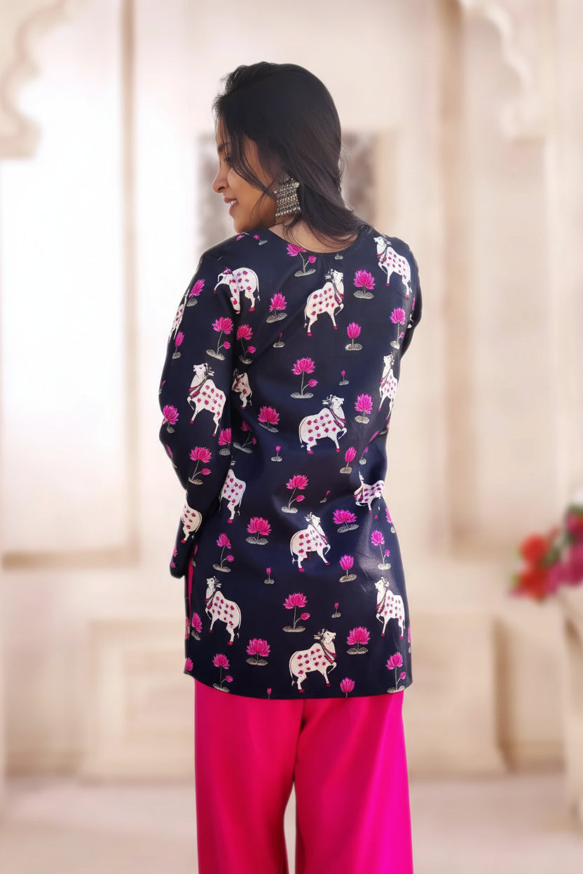 Woman wearing a patterned top and pink Farsi salwar in an indoor setting