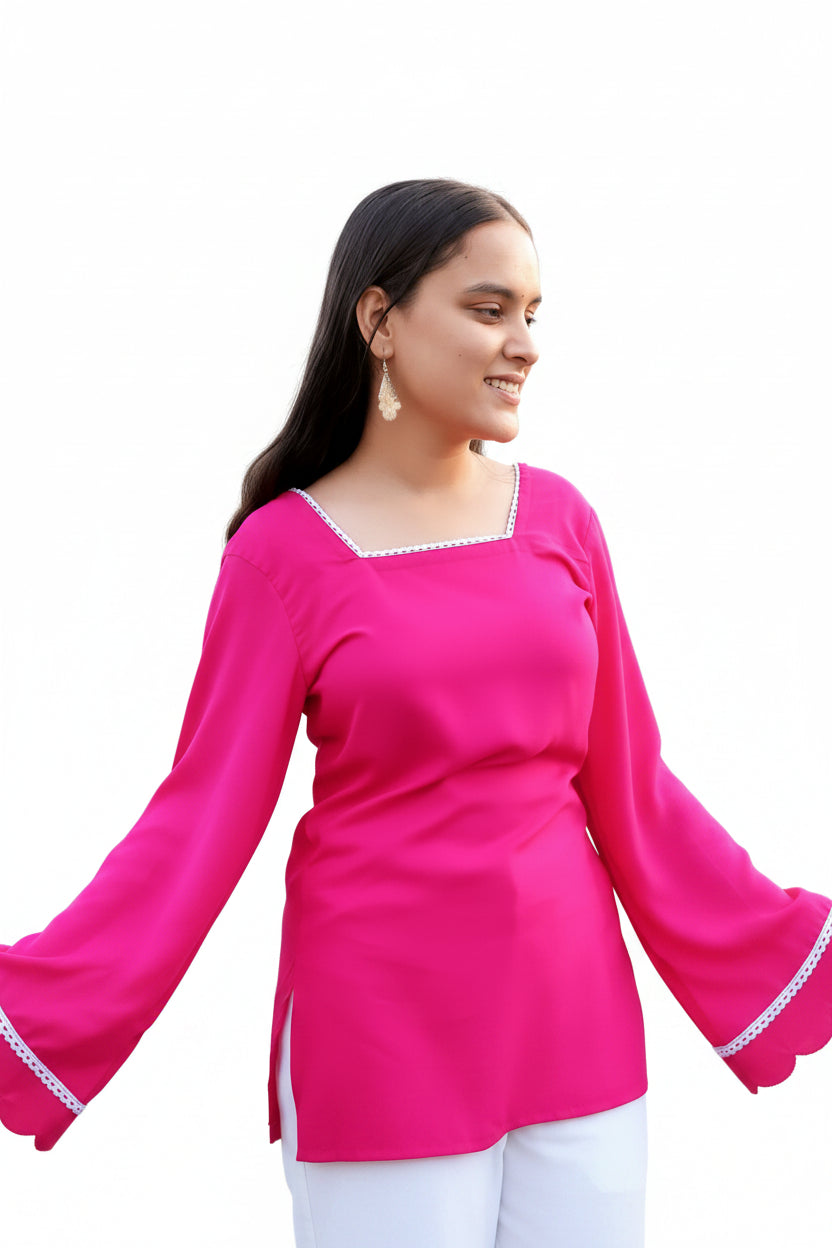 Woman wearing a bright pink top with long sleeves in front of a floral and decorative background