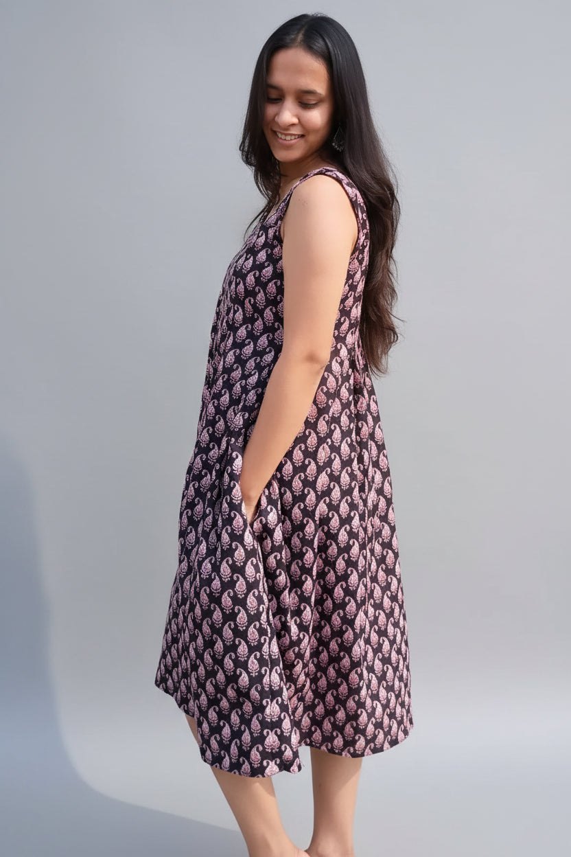 Woman wearing a sleeveless dress with a floral pattern against a plain background