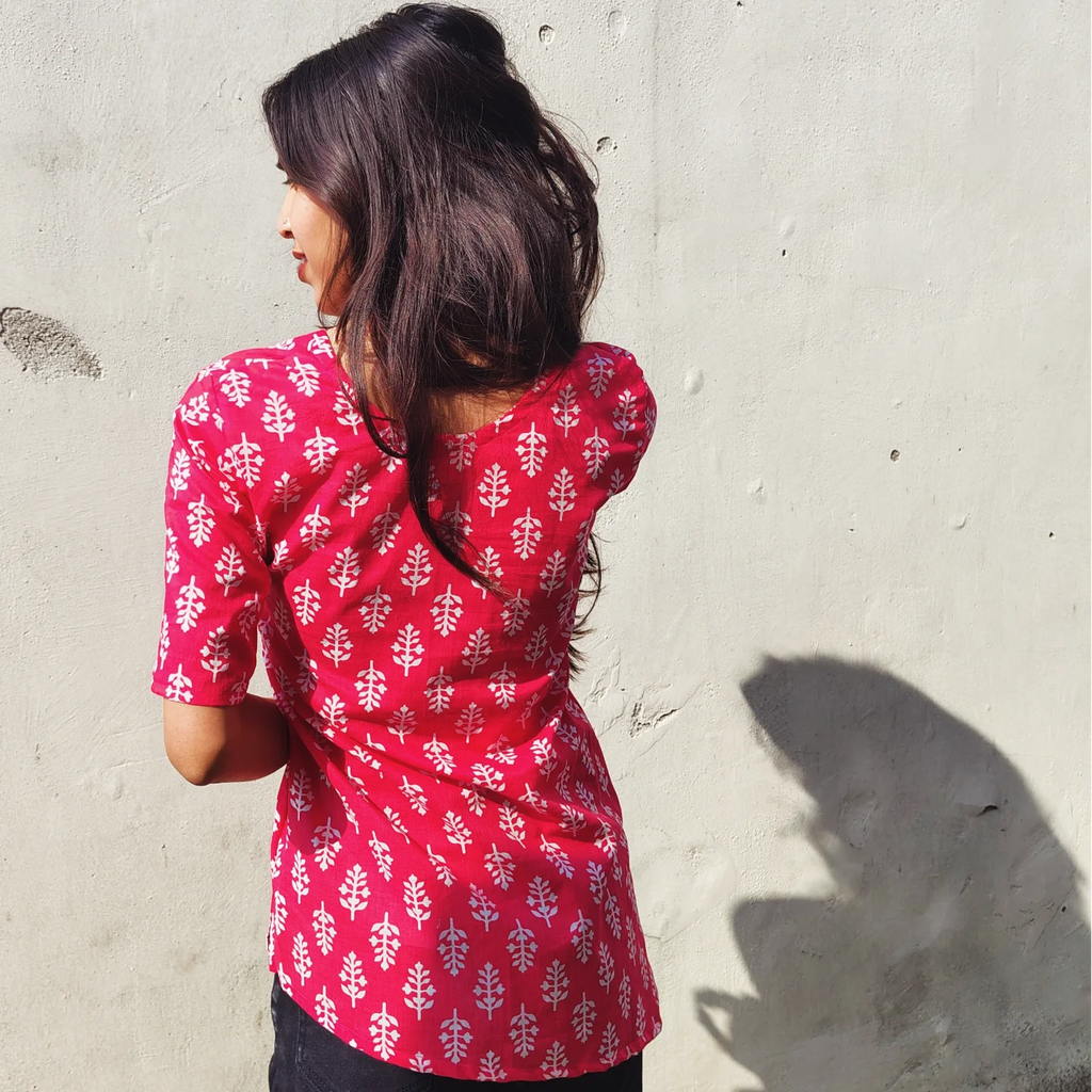 Woman wearing a butti print kurti against a light gray wall