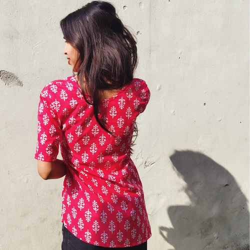 Woman wearing a butti print kurti against a light gray wall