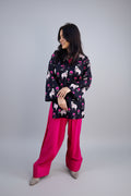 Woman wearing a patterned top and pink salwar in an indoor setting