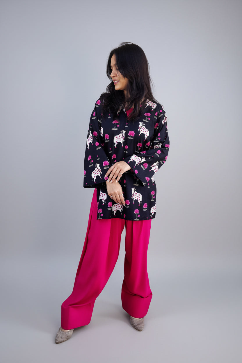 Woman wearing a patterned top and pink salwar in an indoor setting