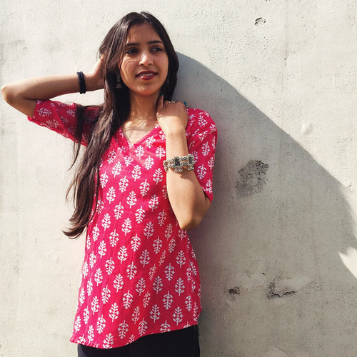 Woman wearing a butti print kurti with white patterns against a gray wall